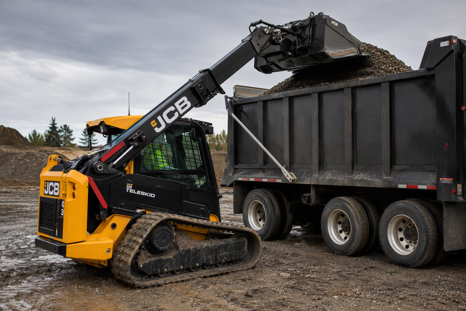 JCB 3TS-8T tracked TeleSkid loading gravel into a high-sided dump truck on a construction jobsite