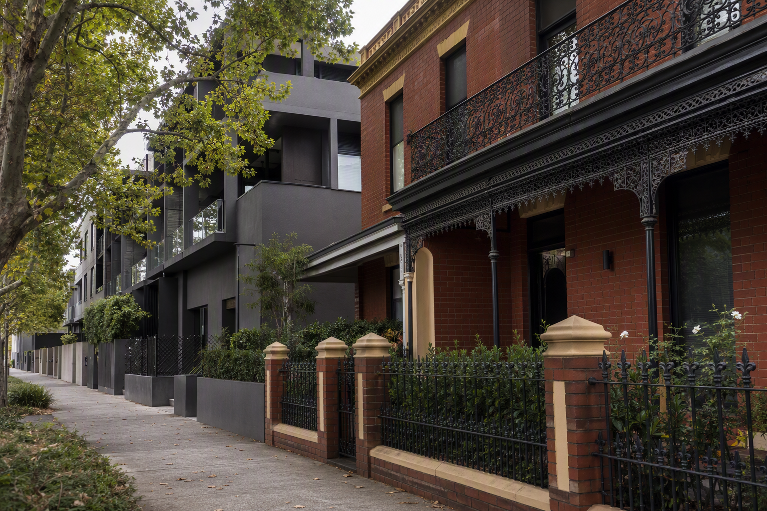 West Melbourne streetscape with red brick Victorian terrace facades beside a modern rendered apartment building