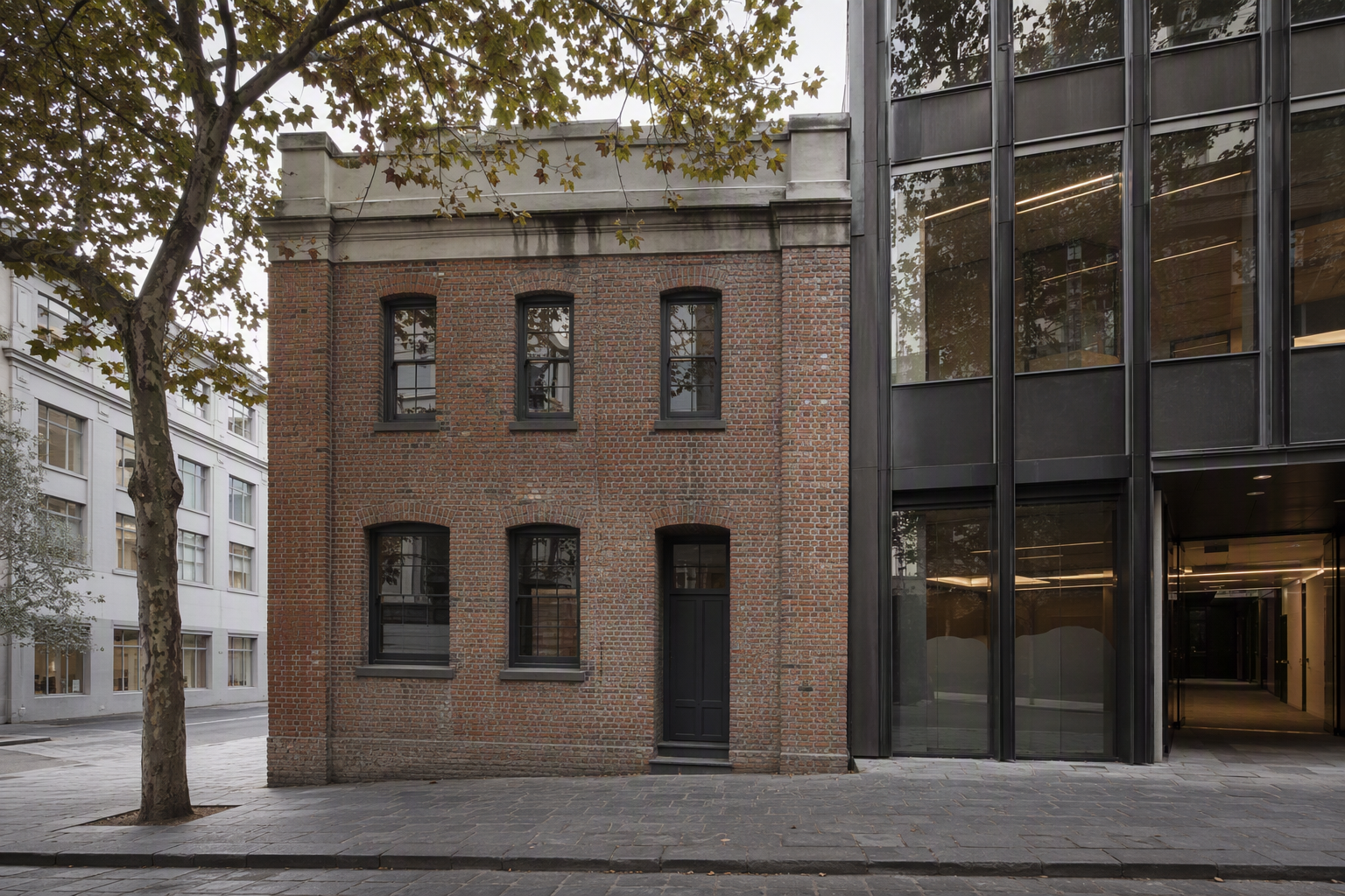 Inner Melbourne corner where a heritage brick building meets a contemporary glass and dark metal office frontage