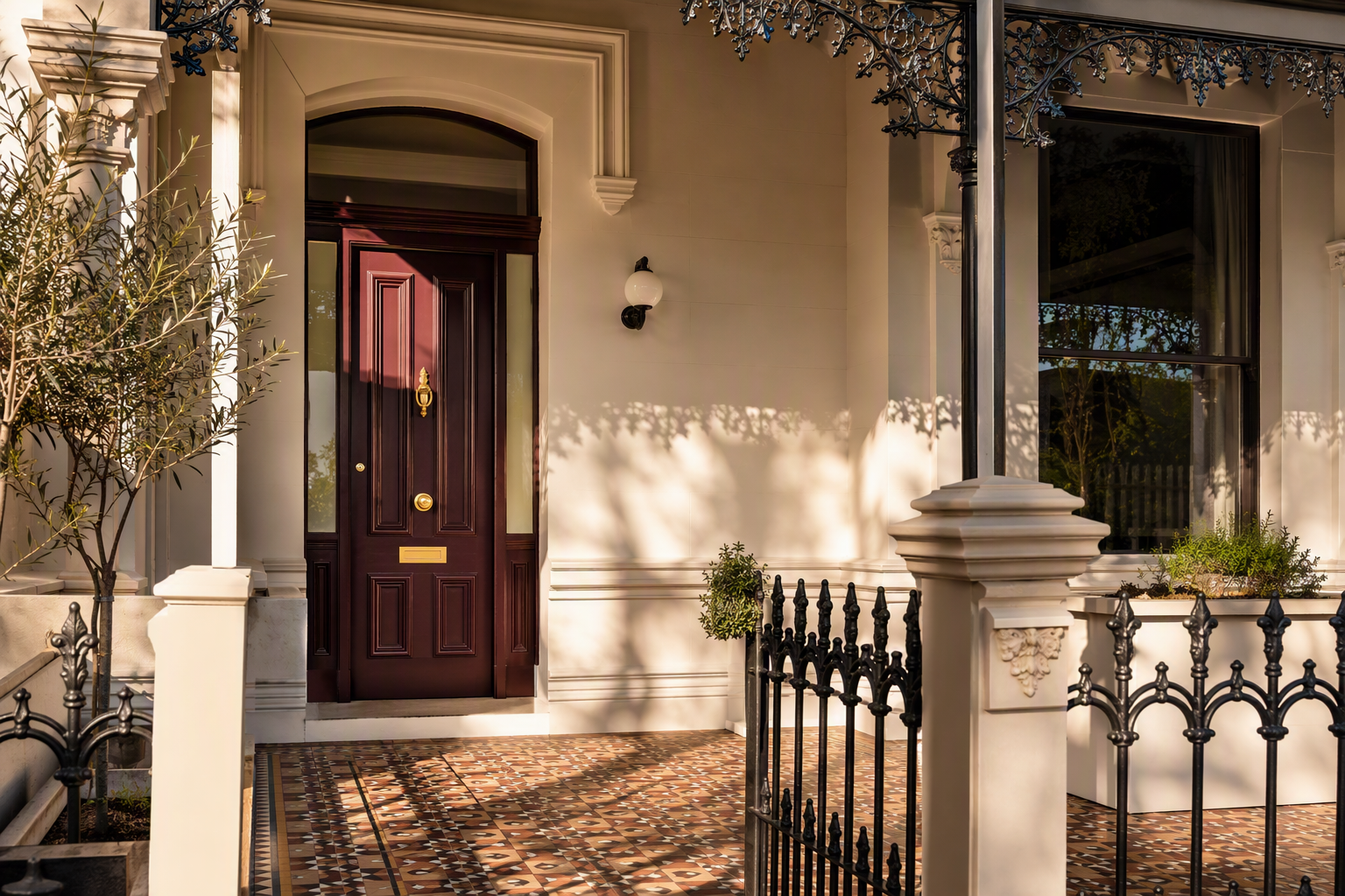 Renovated Melbourne Victorian terrace entrance with a deep burgundy panelled front door and restored brass hardware