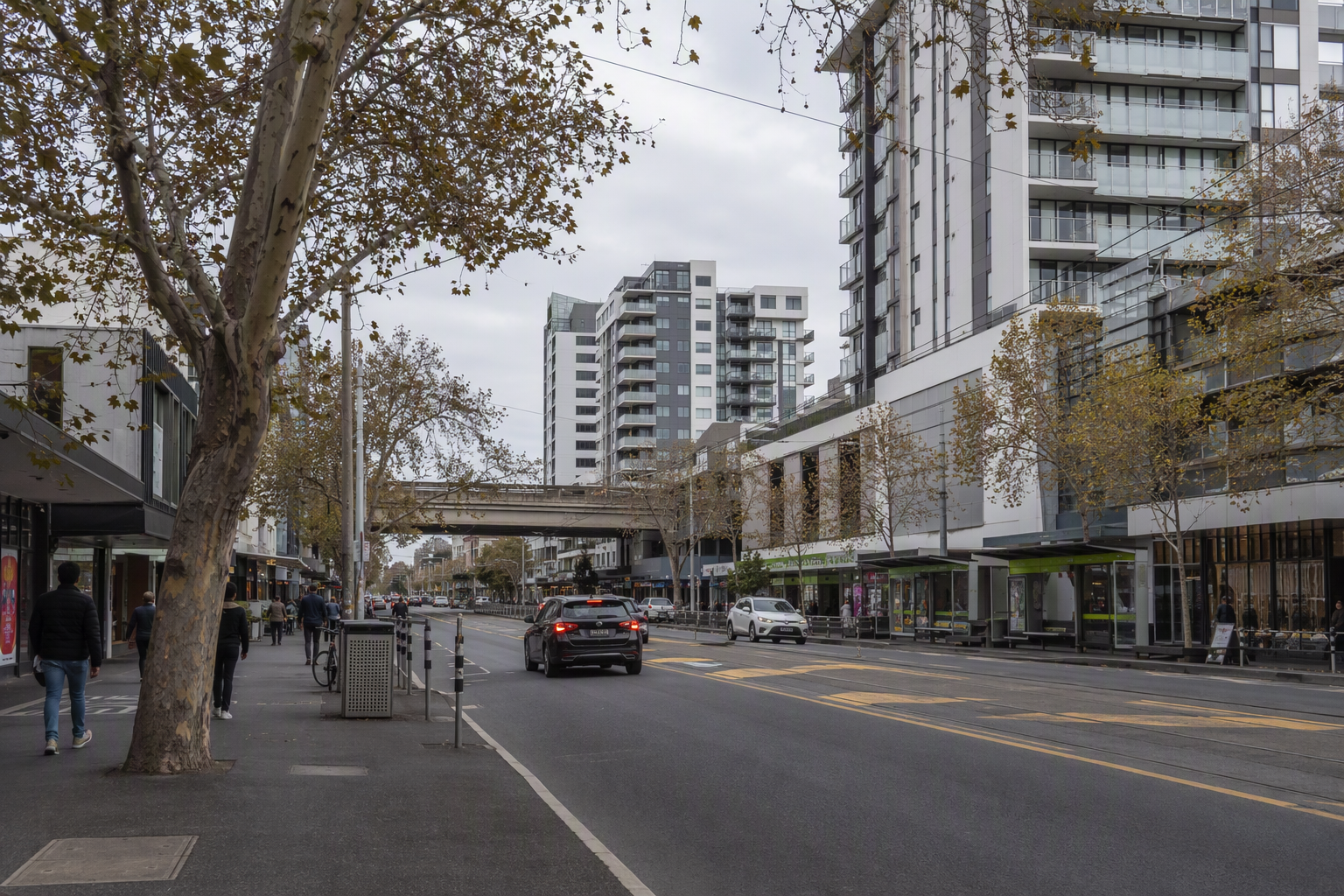 Busy eastern-suburbs Melbourne shopping strip with apartment towers behind low retail shopfronts