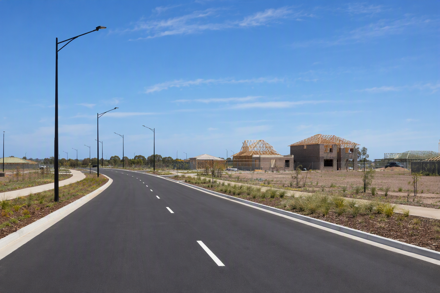 Newly completed roadway with fresh kerbing and light poles through an emerging residential estate at Anketell, Western Australia