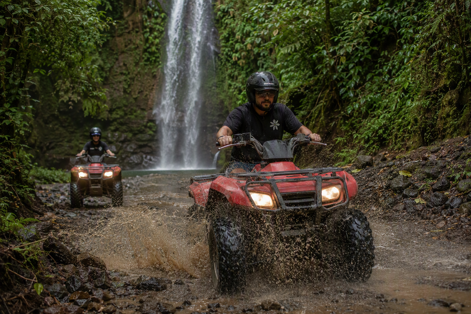 Dos personas en ATV por un sendero de selva con catarata y perezoso de fondo en Jacó